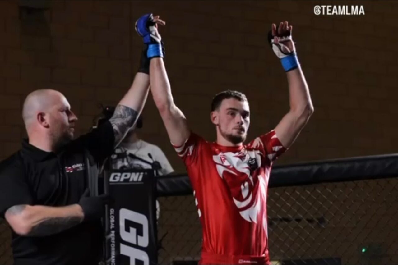 Charlie Lynch-Spence celebrating with both hands raised after a fight in a red Team LMA shirt