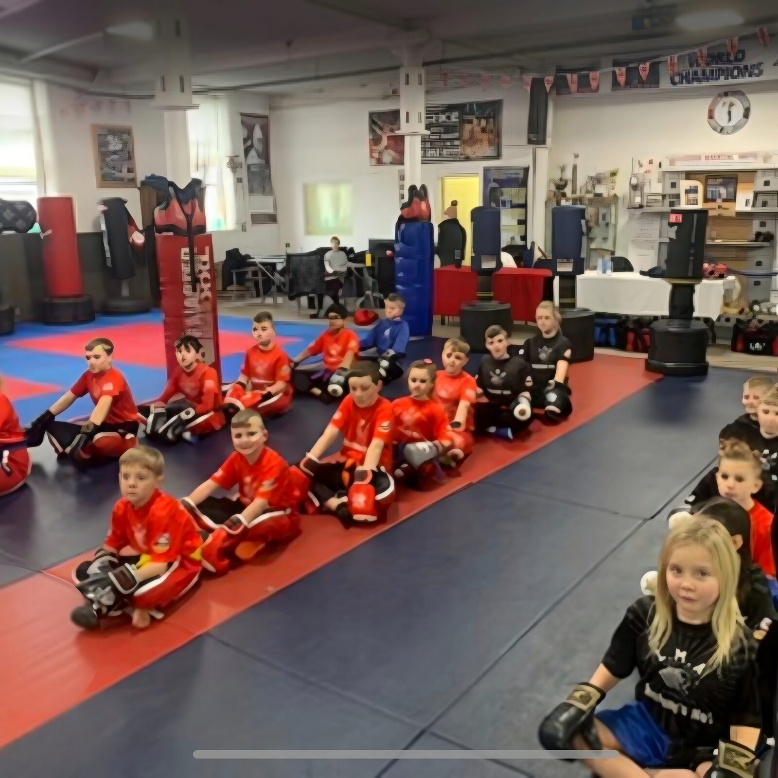 Junior students sitting together in protective equipment on the LMA mats