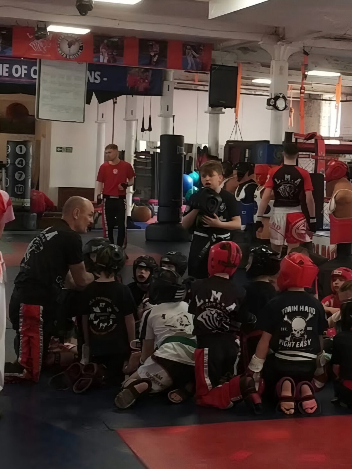 A teacher kneeling with junior students during a training session at LMA
